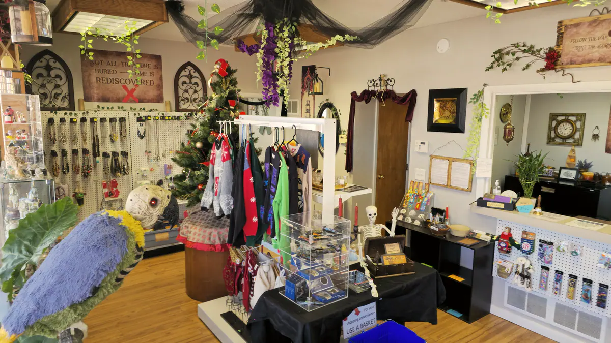 A holiday boutique corner with a decorated tree, clothing rack and gifts
