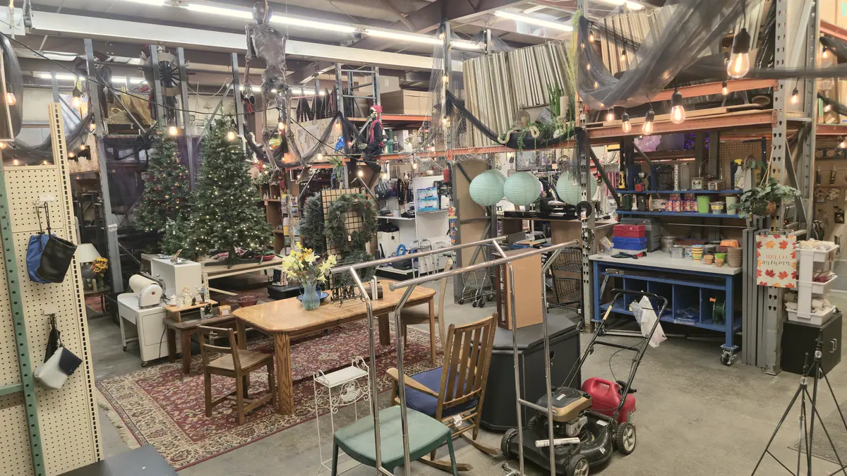 The warehouse under string lights, with furniture, a lit Christmas tree and tools