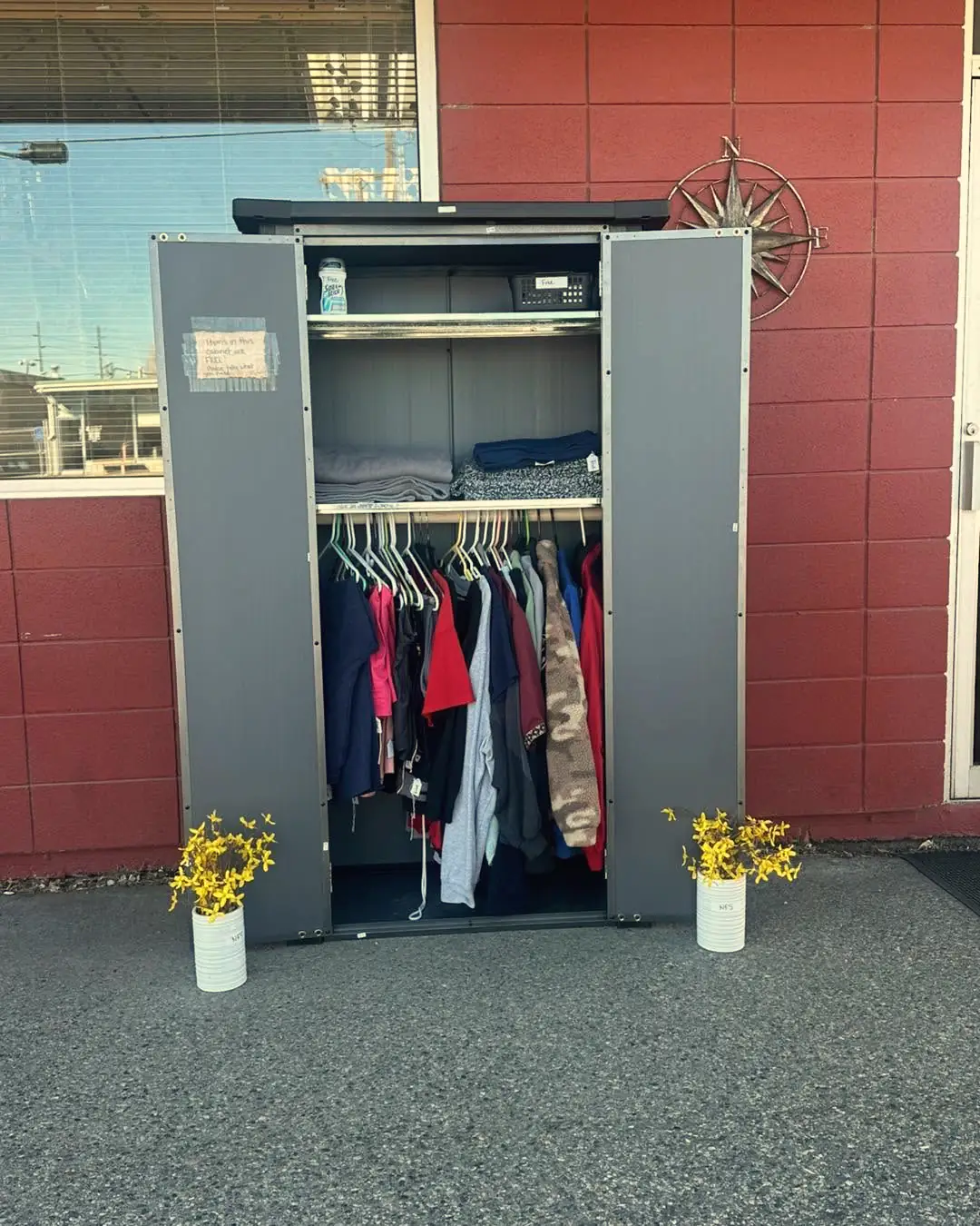 The Free Community Cabinet outside the store, full of coats with flowers either side